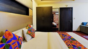 A hotel room with a bed, a ceiling fan, a wardrobe, and a door. - Fabhotel Tip Top (Jaipur)