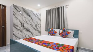 A bedroom with a bed, a marble wall, a window with curtains, and a door.