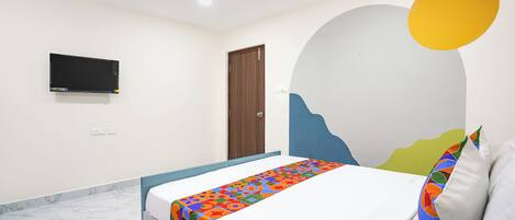 A bedroom with a bed, a TV mounted on the wall, and a door.