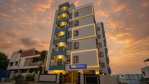 A multi-story hotel with a modern design, featuring balconies on each floor and a prominent sign for 'FabHotels'.