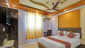 A hotel room with a bed, a TV, a ceiling fan, and an air conditioning unit. - FabExpress Mount City Park (Bangalore)