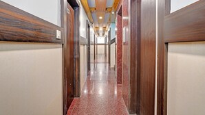 A long, narrow hallway with wooden paneling on the walls and a polished red-tiled floor. - FabExpress Mount City Park (Bangalore)
