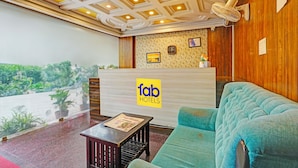 A hotel reception area with a modern design, including a reception desk, a sofa, and a ceiling with recessed lighting. - FabExpress Mount City Park (Bangalore)