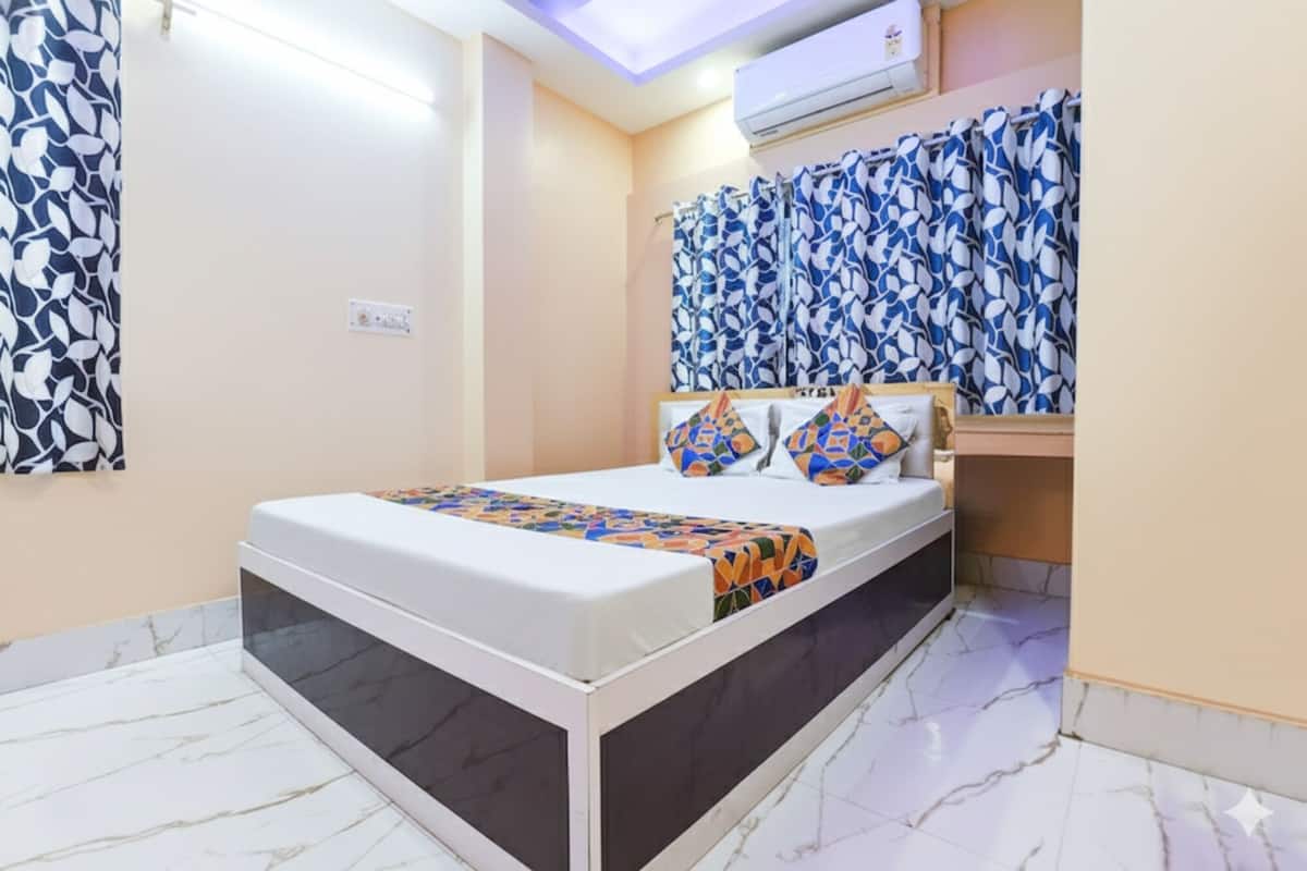 Hotelkamer met een bed, hoofdeinde en gordijnen met patroon, een plafondlamp en een airconditioning.