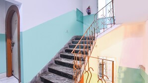 A staircase with a metal railing, a fire extinguisher, and a door at the bottom. - Fabhotel City Palace (Kolkata)