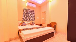 A hotel room with a bed, a chair, an air conditioning unit, and a mirror. - Fabhotel City Palace (Kolkata)