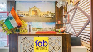 A hotel reception desk with a 'fab hotels' sign, a flag, and a framed photo of a building. - Fabhotel Travellers (Lucknow)