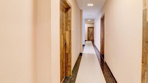 A long, narrow hallway with wooden doors on both sides, leading to a room at the end. - Fabhotel Travellers (Lucknow)