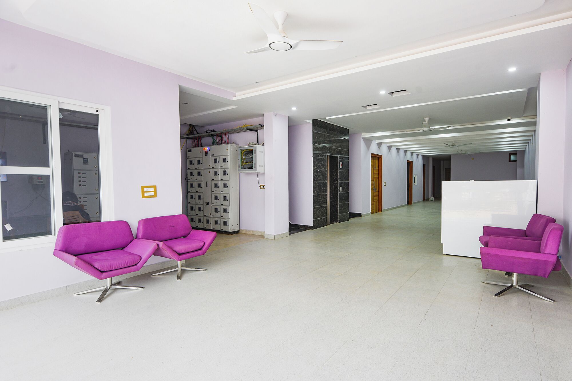 A modern waiting area with purple chairs, a reception desk, and a hallway leading to other rooms.