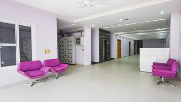 A modern waiting area with purple chairs, a reception desk, and a hallway leading to other rooms.
