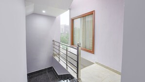A modern interior with a staircase, a window with a wooden frame, and a metal railing. - FabHotel Naveen Stay (Gurugram)