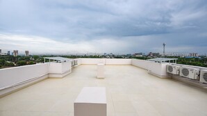 A rooftop terrace with a clear view of the city skyline, air conditioning units, and a flat surface. - FabHotel Naveen Stay (Gurugram)