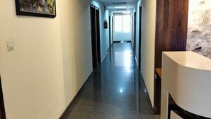 Un long couloir étroit, doté d’un plancher poli, qui mène à une pièce dont la porte est en bois.