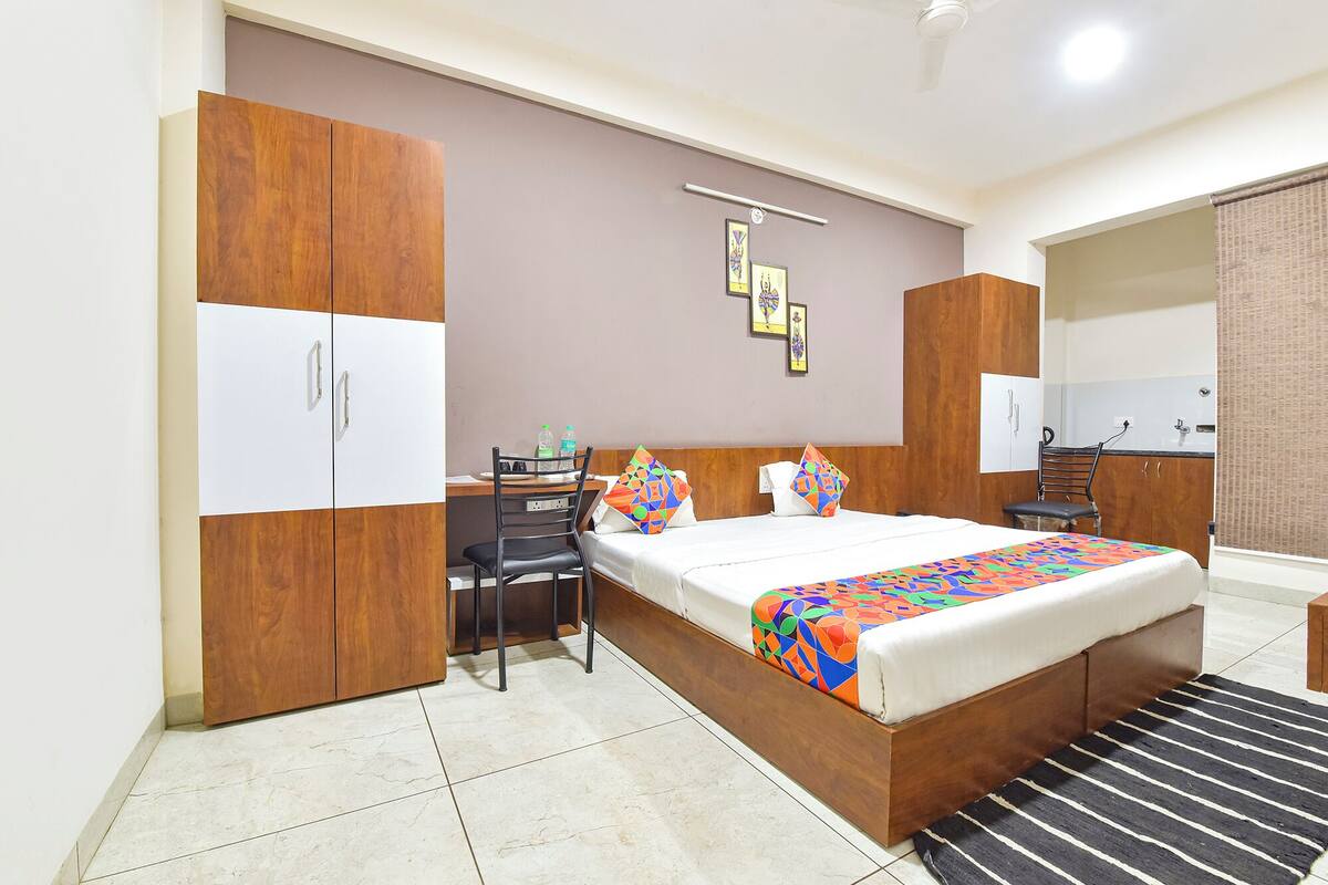 A bedroom with a bed, a desk, and a wardrobe.