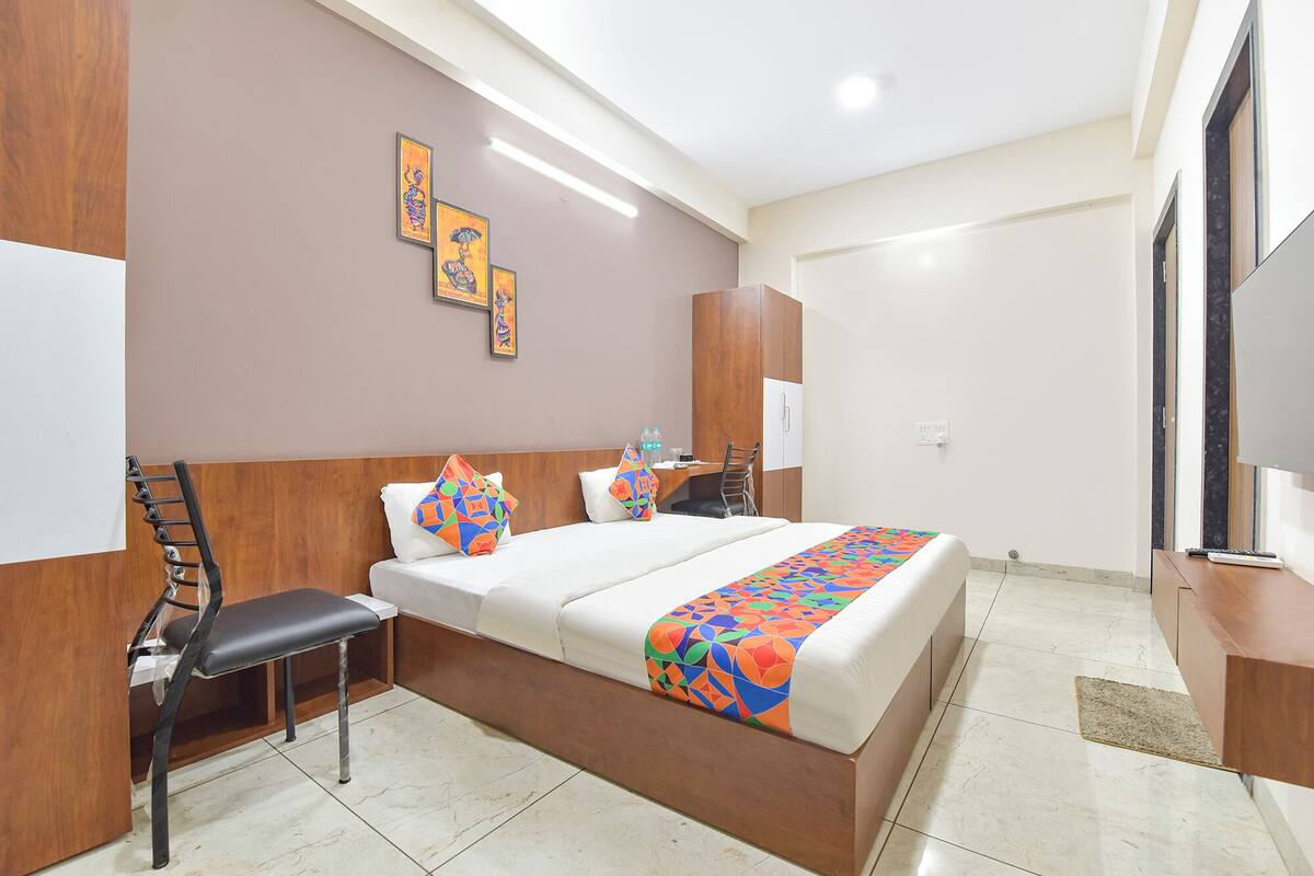 A hotel room with a bed, a desk, a chair, a wardrobe, and a television.