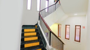 A staircase with black and yellow steps, white walls, and a wooden handrail. - Fabhotel Panchratna (Panvel)