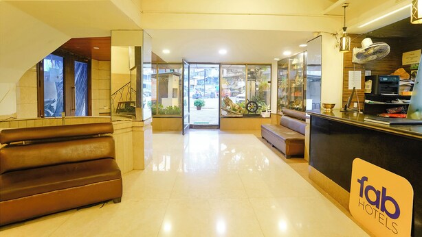 A hotel lobby with a reception desk, seating area, and a view of the street outside. - Fabhotel Panchratna (Panvel)