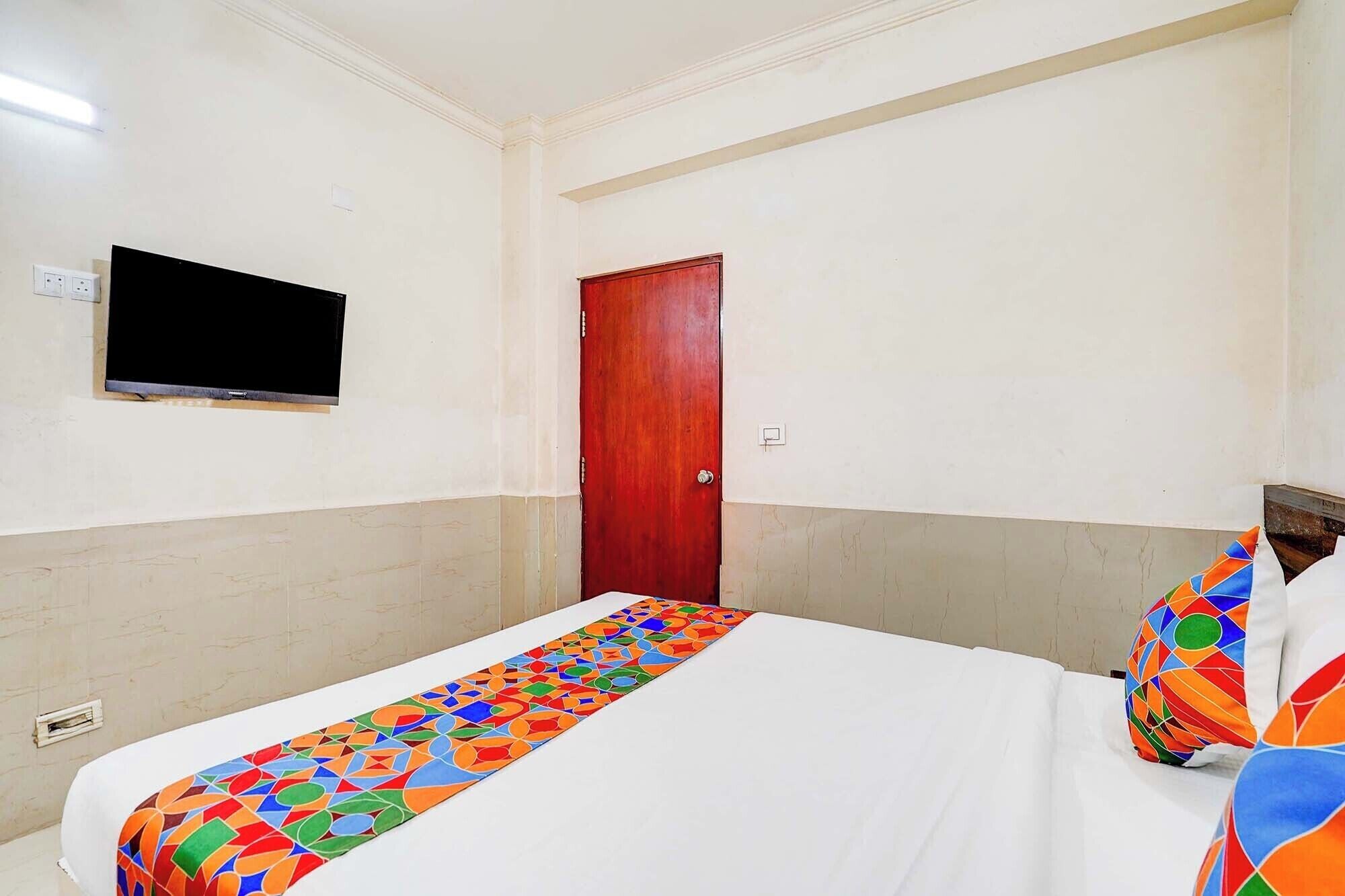 A hotel room with a bed, a television mounted on the wall, and a door.