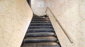 Una escala de marbre amb barana, que condueix a un badiu amb un interruptor de llum.