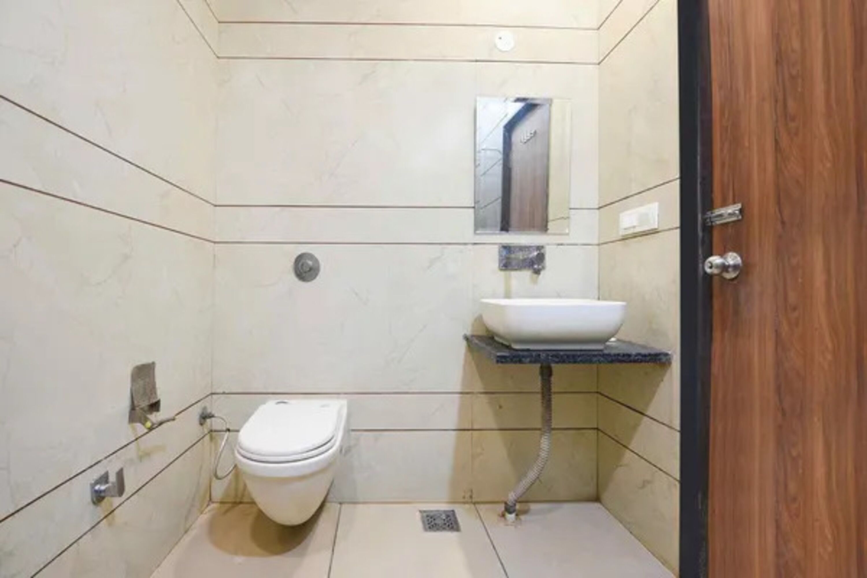 A small, modern bathroom with a toilet, sink, and mirror.