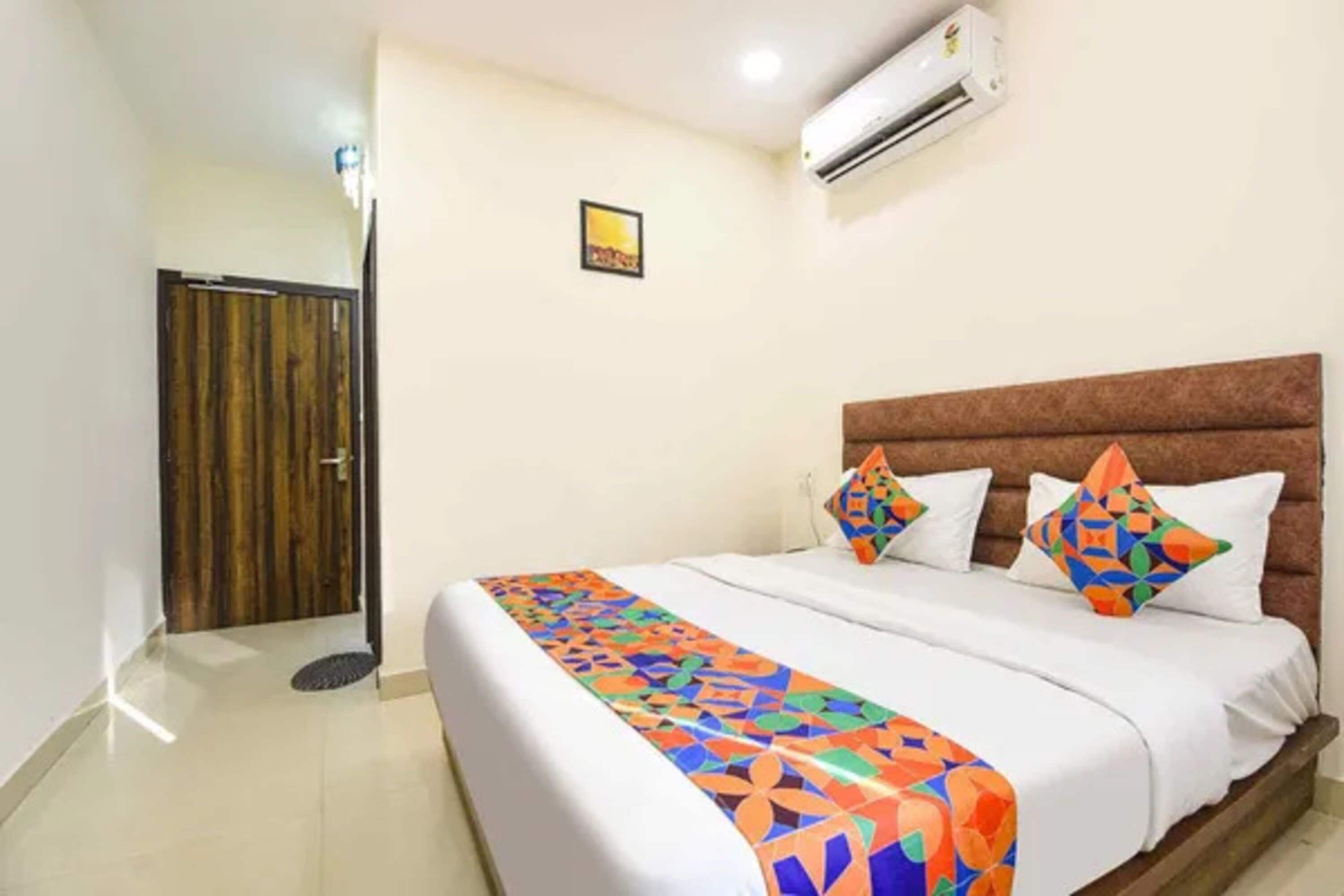 Una habitación de hotel con una cama, cabecera marrón y colcha colorida.
