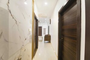 A hallway with marble walls, wooden doors, and a light-colored floor. - Fabhotel Classic Comfort (Amritsar)
