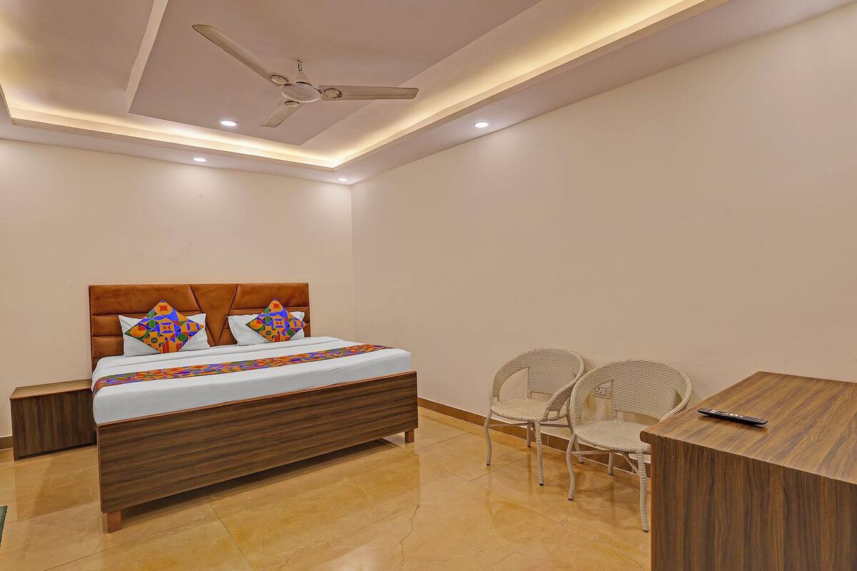 A bedroom with a wooden bed, two wicker chairs, a small wooden table, and a ceiling fan.
