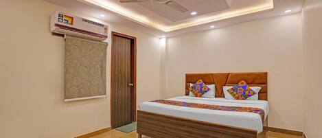 Habitación de hotel con cama, ventilador de techo, equipo de aire acondicionado y cortina estampada.