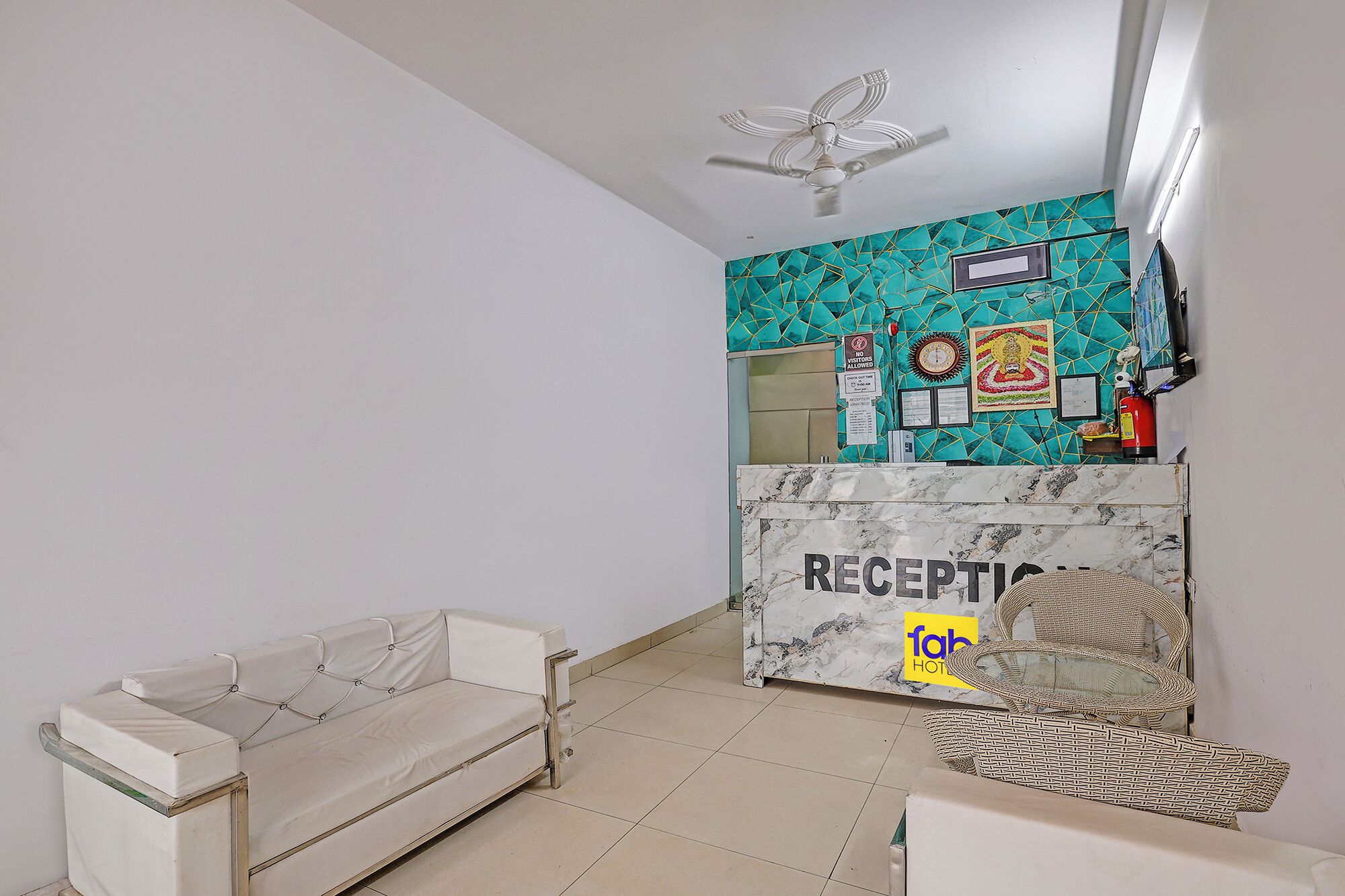 A reception area with a marble counter, a sofa, wicker chairs, and a ceiling fan.