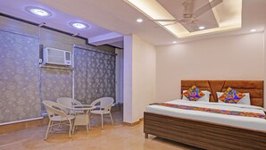 Un dormitorio con cama, dos sillas, ventilador de techo y pared con diseño.