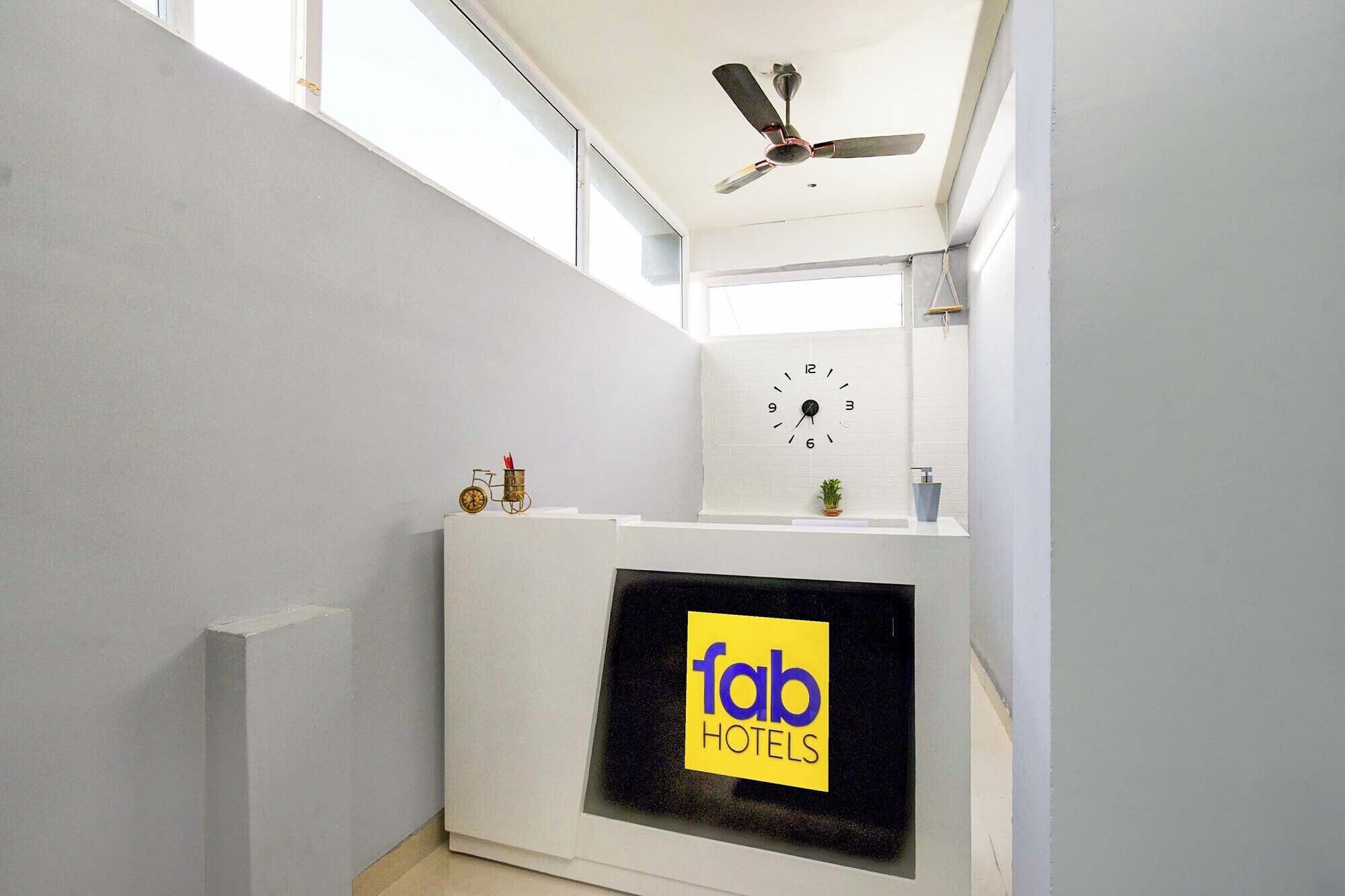 Zona de recepción de hotel con un reloj, un ventilador de techo y un cartel que dice 'fab hotels'.