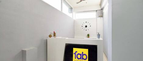 Zona de recepción de hotel con un reloj, un ventilador de techo y un cartel que dice 'fab hotels'.
