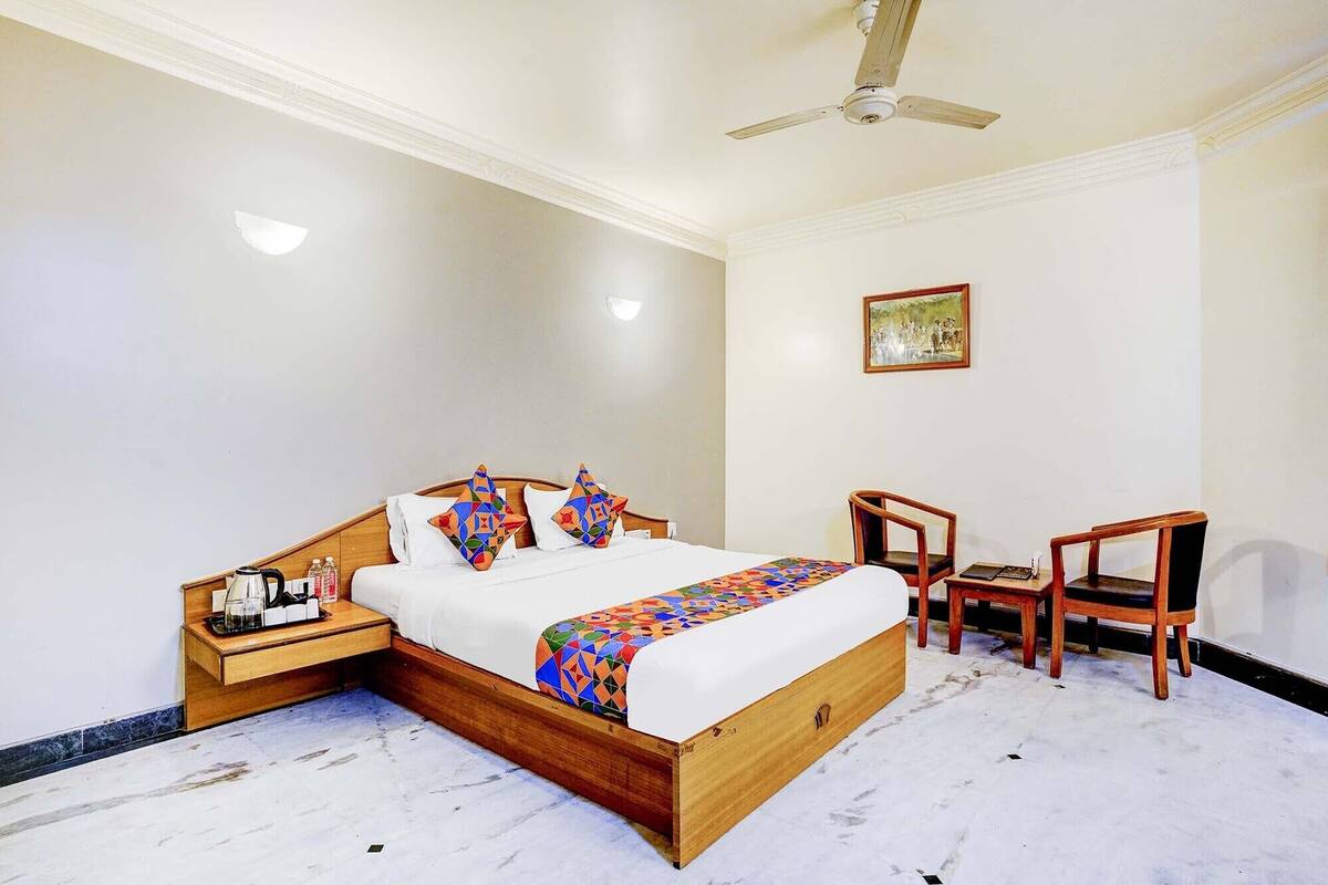 A bedroom with a wooden bed, two nightstands, a ceiling fan, and two wooden chairs.