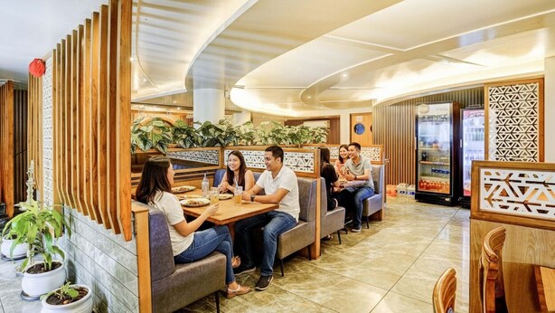 Un restaurant moderne avec des cloisons en bois, un aménagement soigné et des plantes en pot.