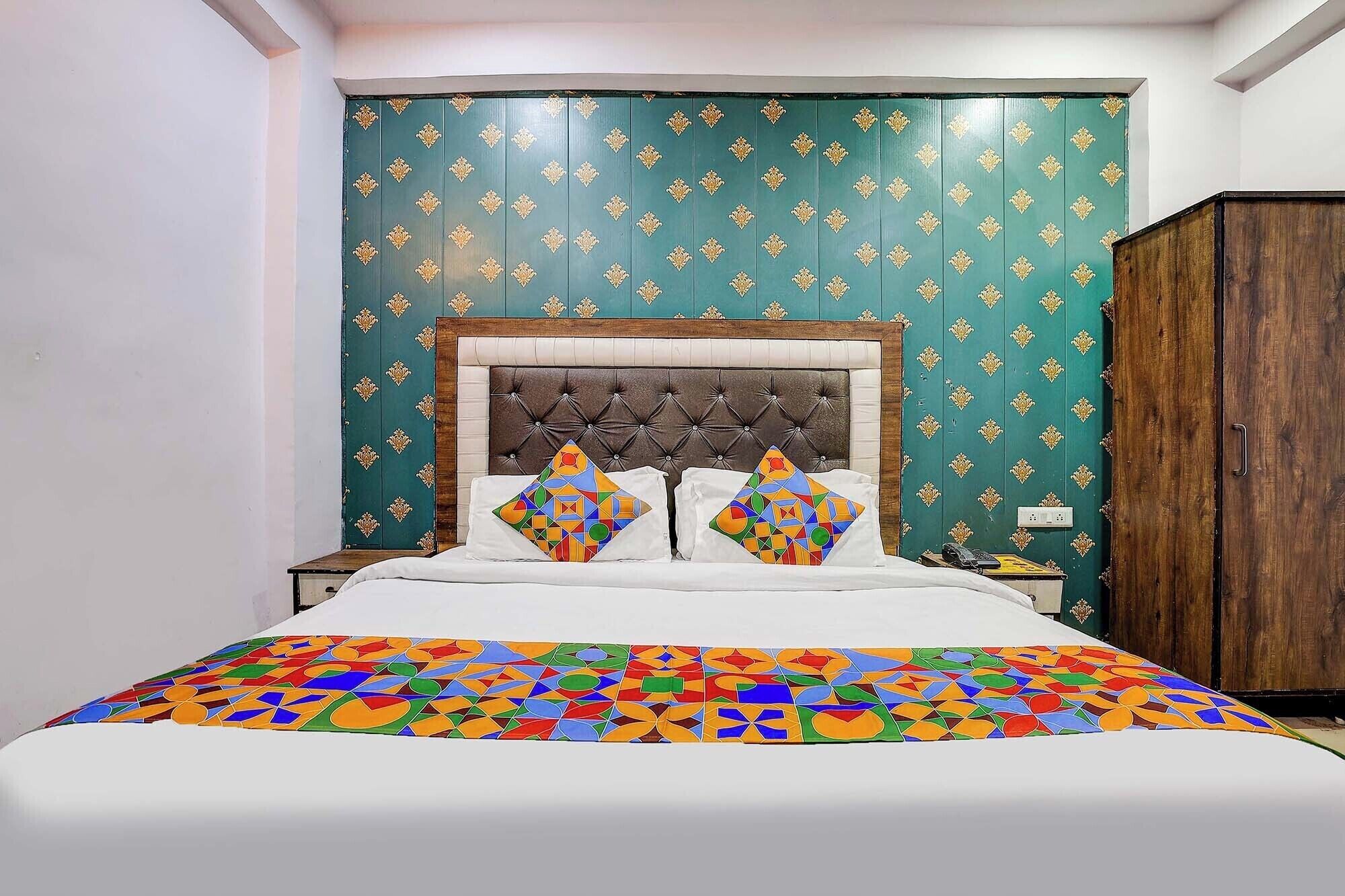 A bed with a colorful geometric-patterned bedspread, a tufted headboard, and two decorative pillows.