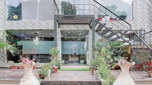 A building entrance with a glass door, steps leading up to a balcony, and potted plants. - FabHotel Golden Stone (Ghaziabad)