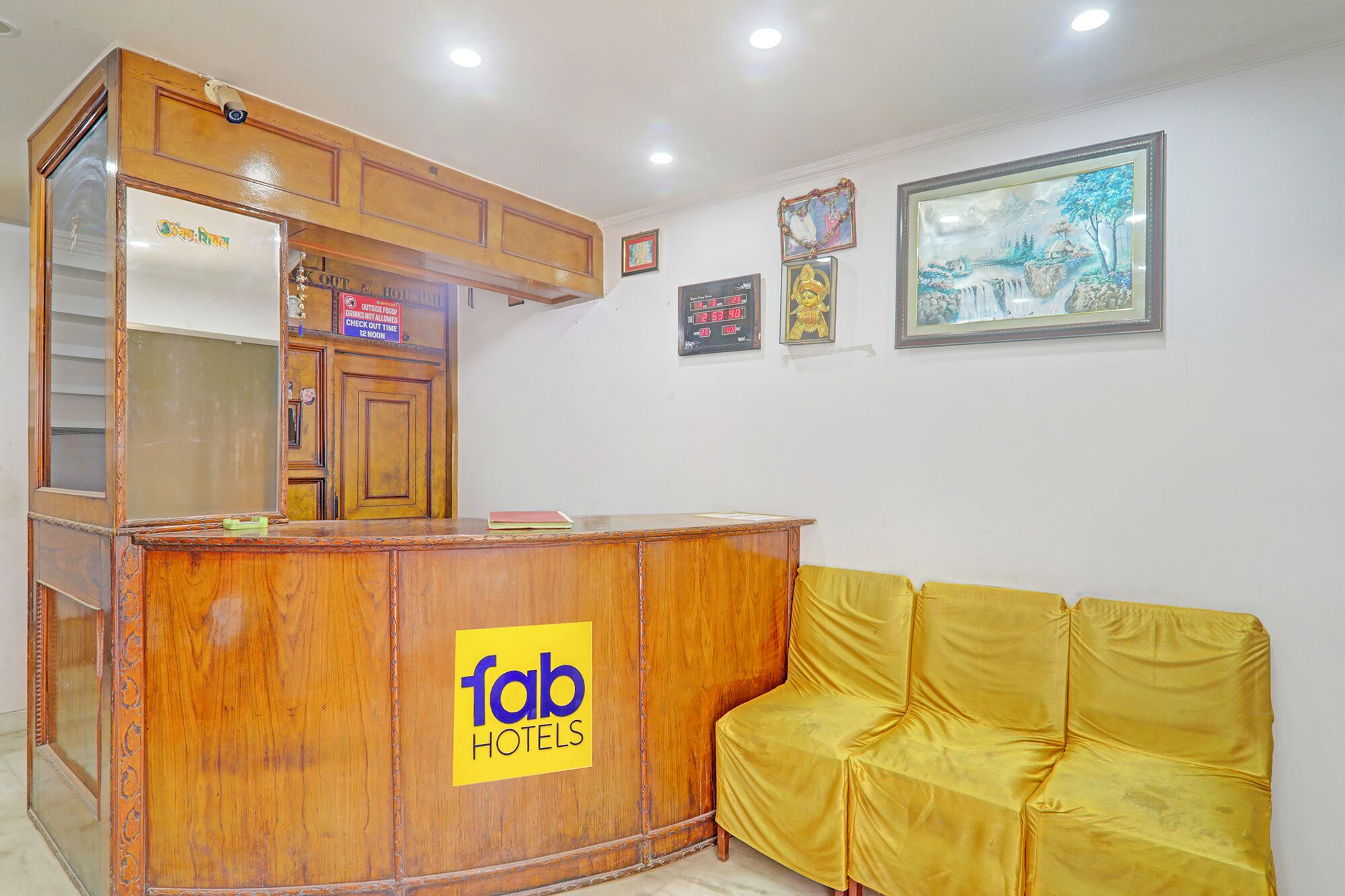 Un taulell de recepció amb el logotip de 'fab hotels', un sofà groc i obra emmarcada a la paret.