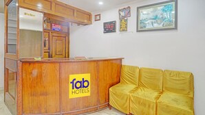 A reception desk with a 'fab hotels' logo, a yellow sofa, and framed artwork on the wall. - Fabhotel Anant (Lucknow)