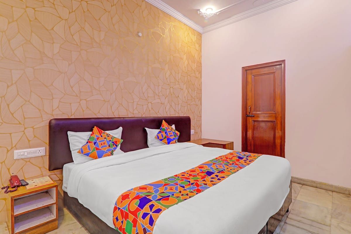 Une chambre d’hôtel avec un lit, une table de chevet en bois, un téléphone et une porte.