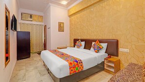 A hotel room with a large bed, a wooden nightstand, a patterned wall, and a tiled floor. - Fabhotel Anant (Lucknow)