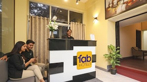 Un área de recepción con un mostrador blanco y negro, un letrero que dice 'fab hotels' y una planta en maceta.