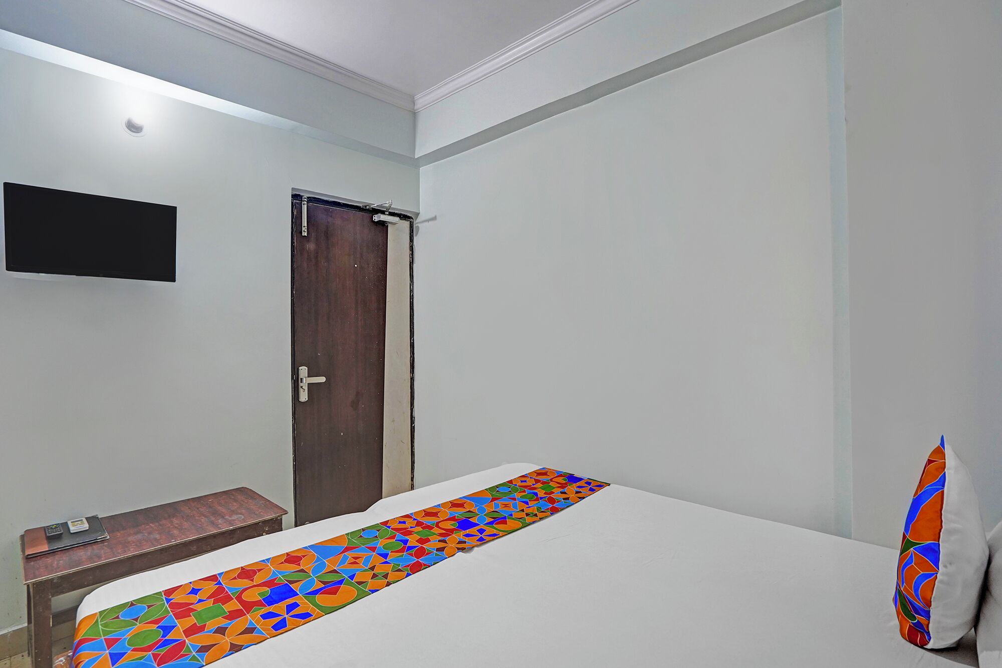 Une chambre avec un lit, une petite table, une télévision et une porte.