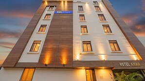 A modern hotel building with a flat roof, multiple windows, and a sign for 'Tab Hotels' and 'Hotel Aman'.