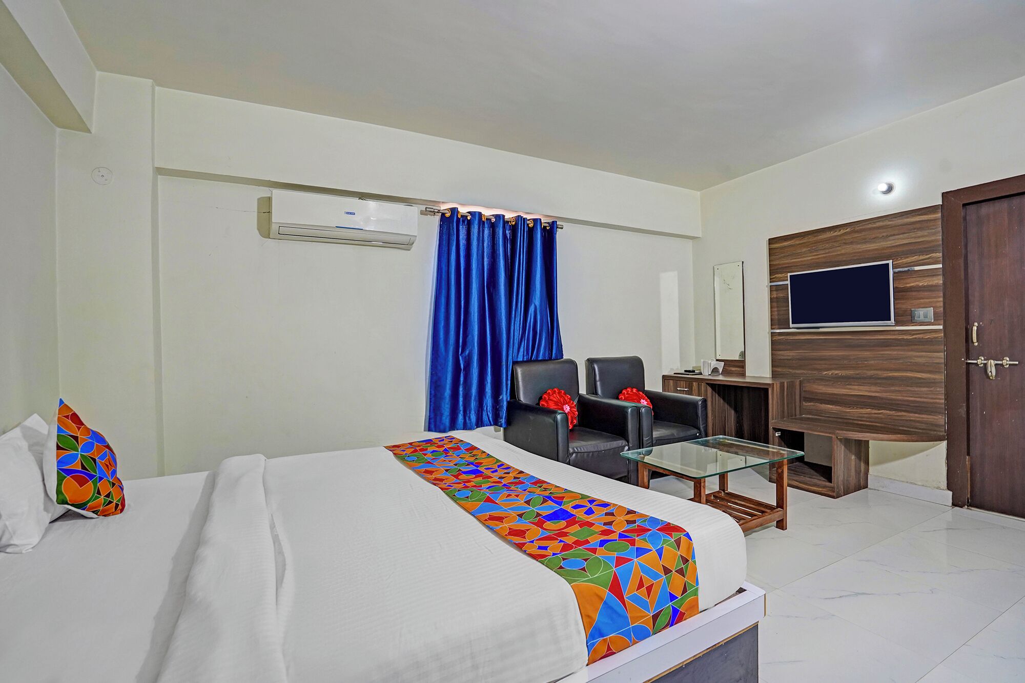 A hotel room with a bed, a desk, a chair, a TV, and a wardrobe.