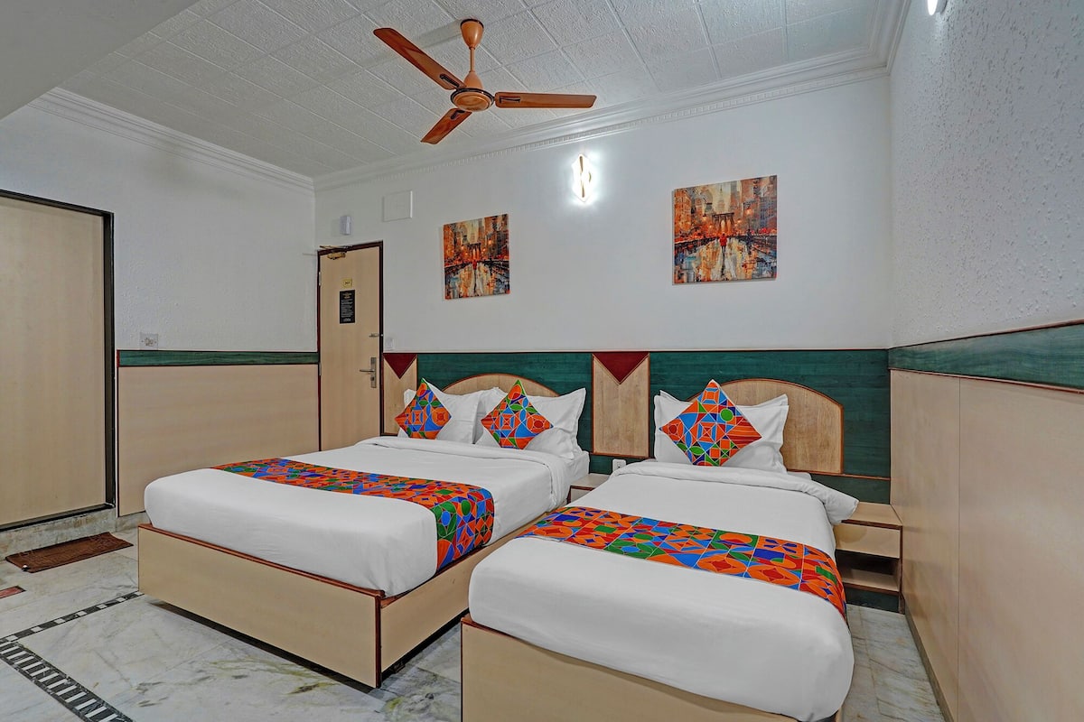 A hotel room with two beds, a ceiling fan, and artwork on the walls.