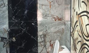 A bathroom with black and white marble tiles, a white toilet, and a shower area. - Fabhotel Arya Baner (Pune)