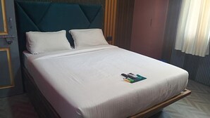 A hotel room with a bed, a wooden headboard, and a window with curtains. - Fabhotel Arya Baner (Pune)