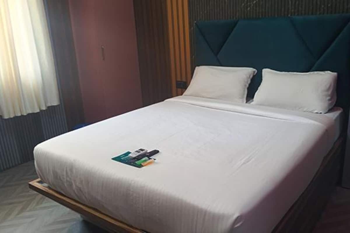 A neatly made bed with a white bedspread and pillows, a wooden headboard, and a small magazine on the bed.
