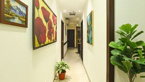 A hallway with framed artwork on the walls, a potted plant, and a door at the end. - Fabhotel Motisarai (Kolkata)