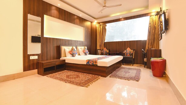 A modern bedroom with a large bed, a desk, and a TV. - Fabhotel Motisarai (Kolkata)